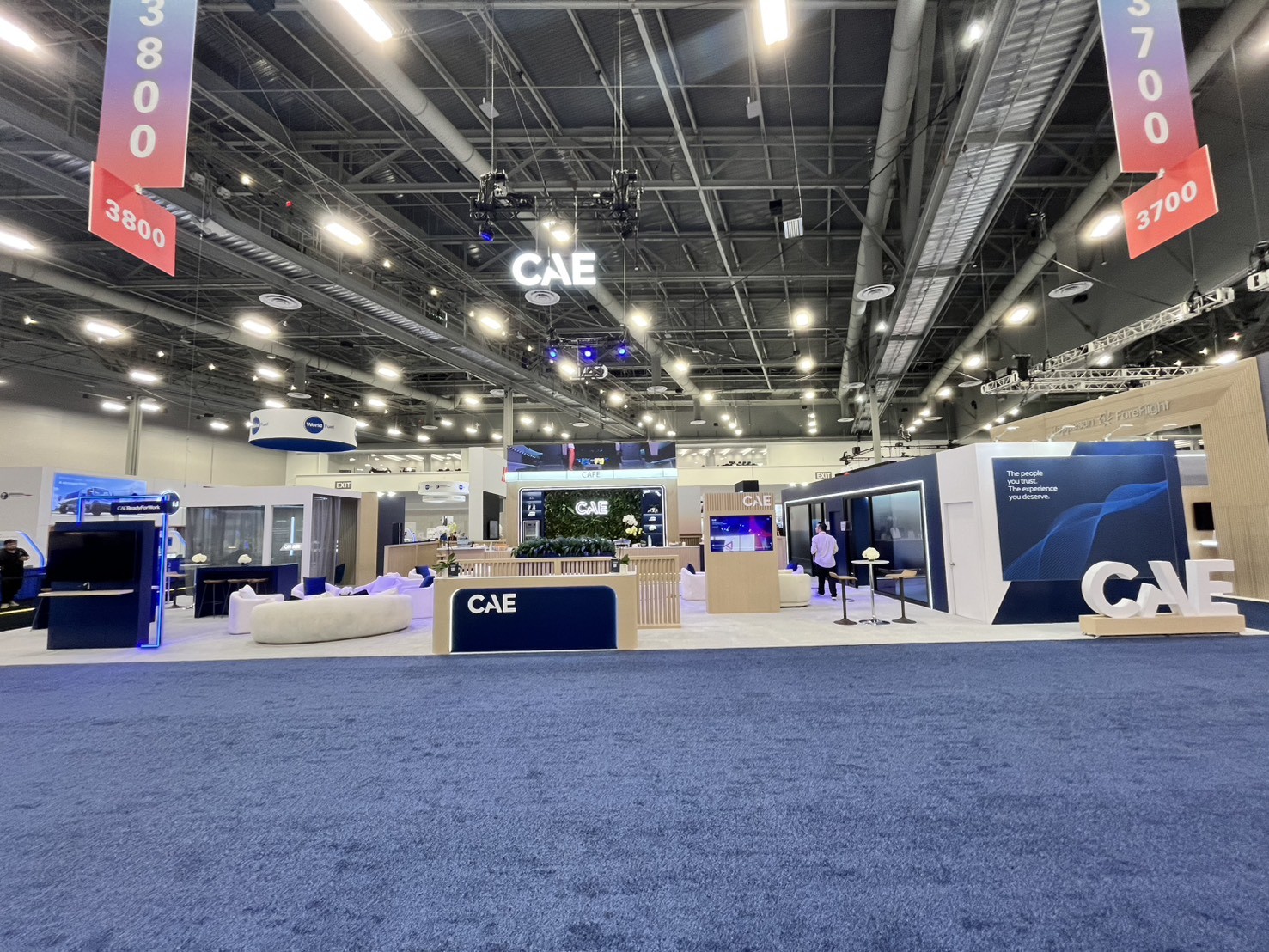 wide view of the CAE island with the hanging CAE sign, café counter, lounge seating, and large CAE letters