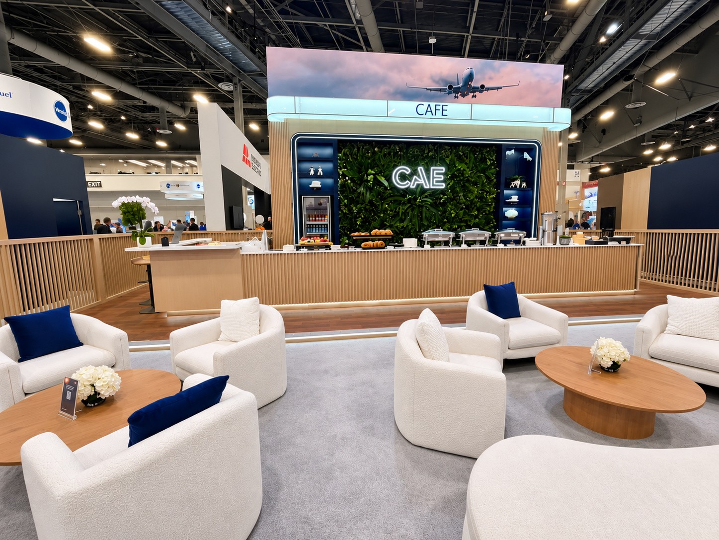 Café counter in wood slats with a green living wall and the CAE logo above.