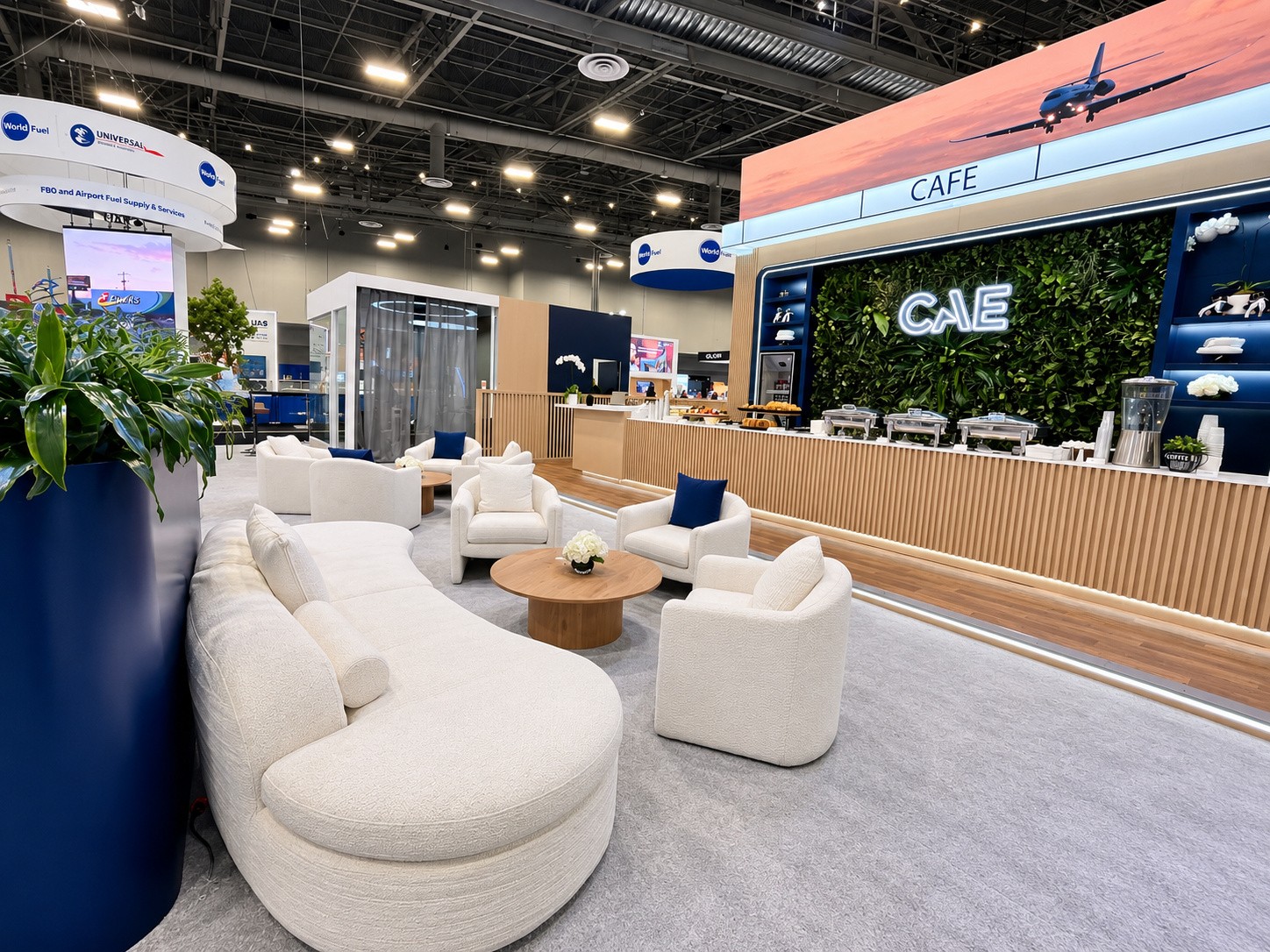 White lounge seating around wood tables with the café counter and living wall behind.