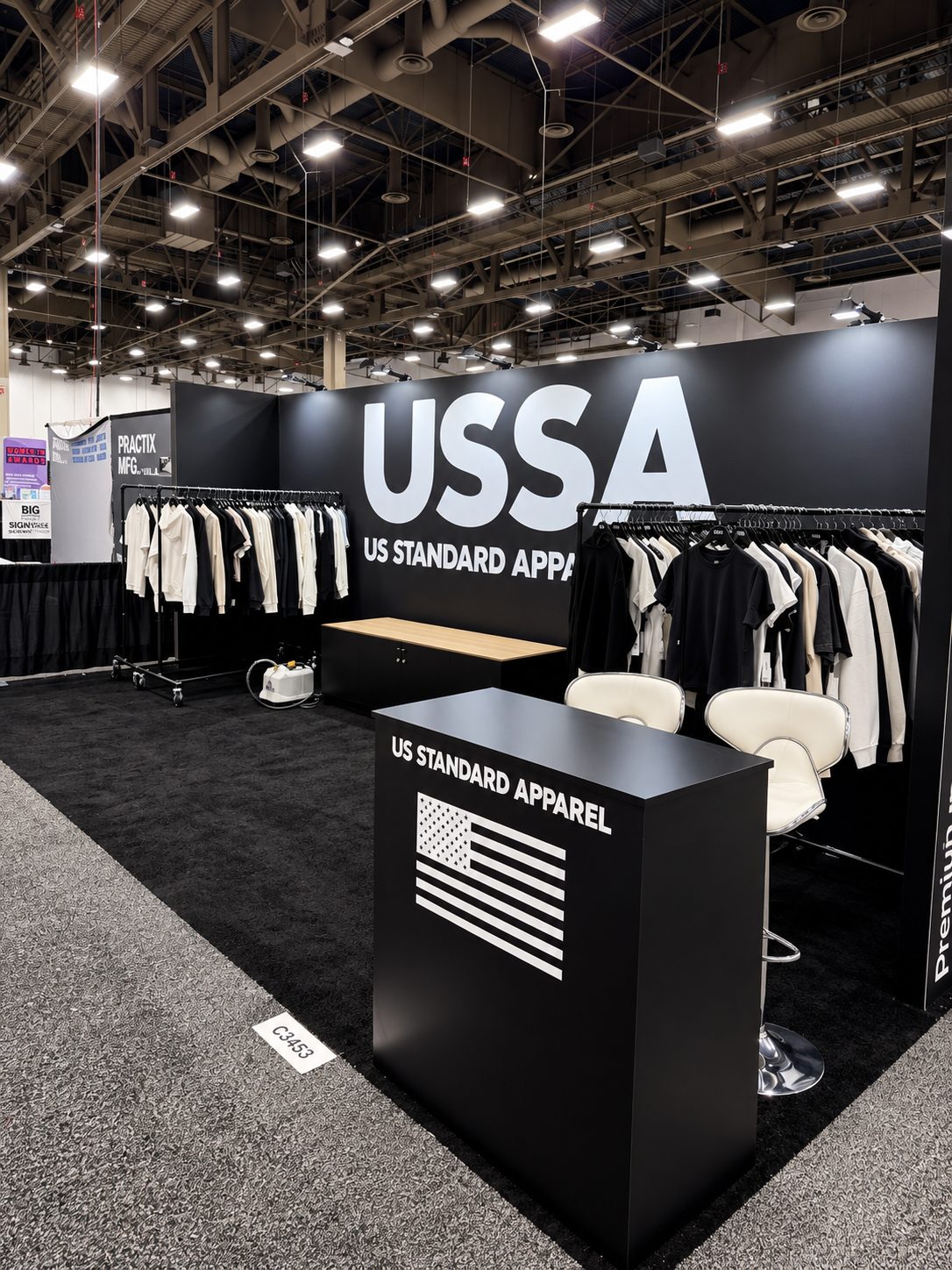 US Standard Apparel podium with the flag graphic beside the wood-top counter and apparel racks
