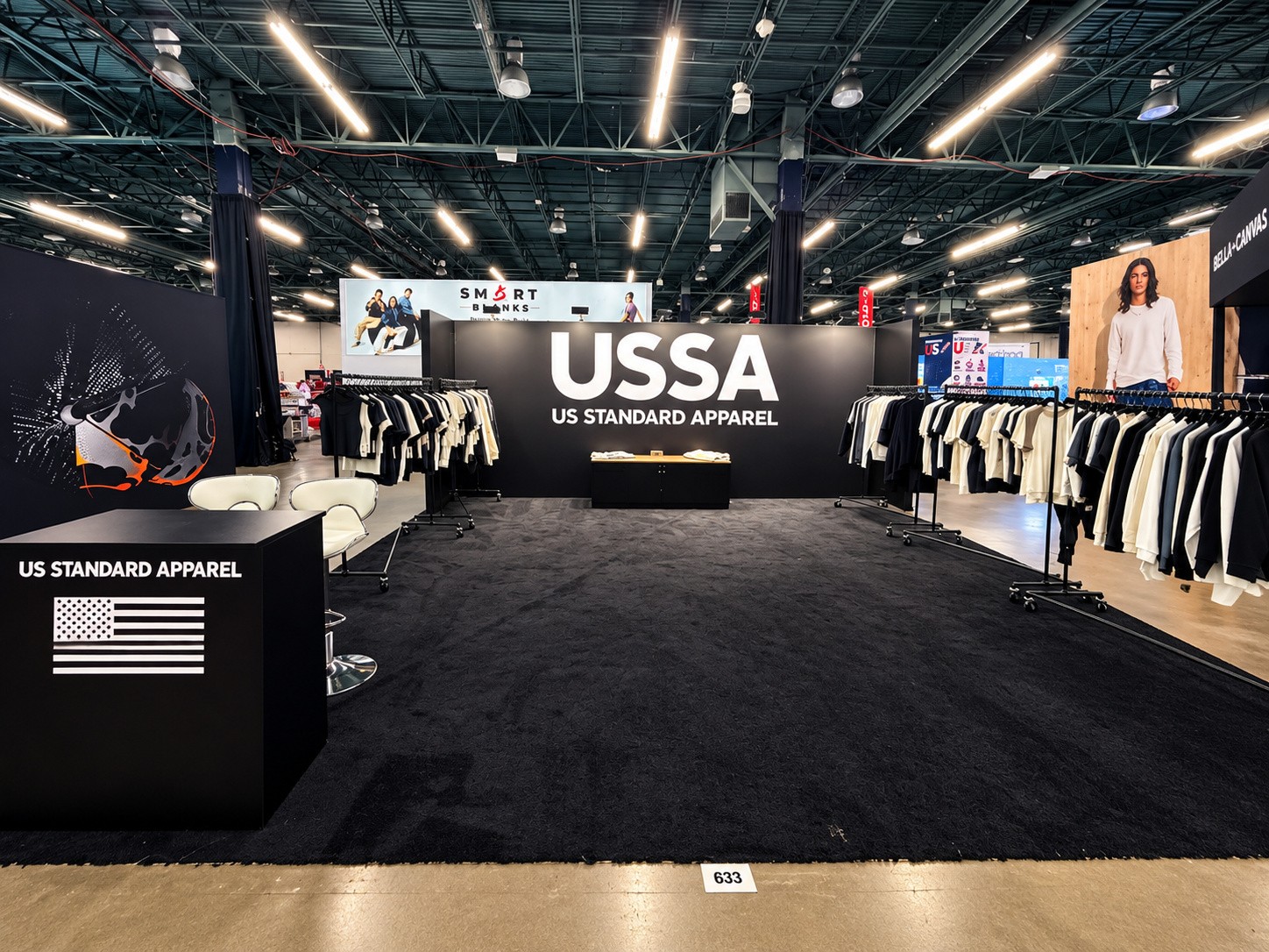 USSA island with a black wall reading USSA over US STANDARD APPAREL and garment racks on both sides