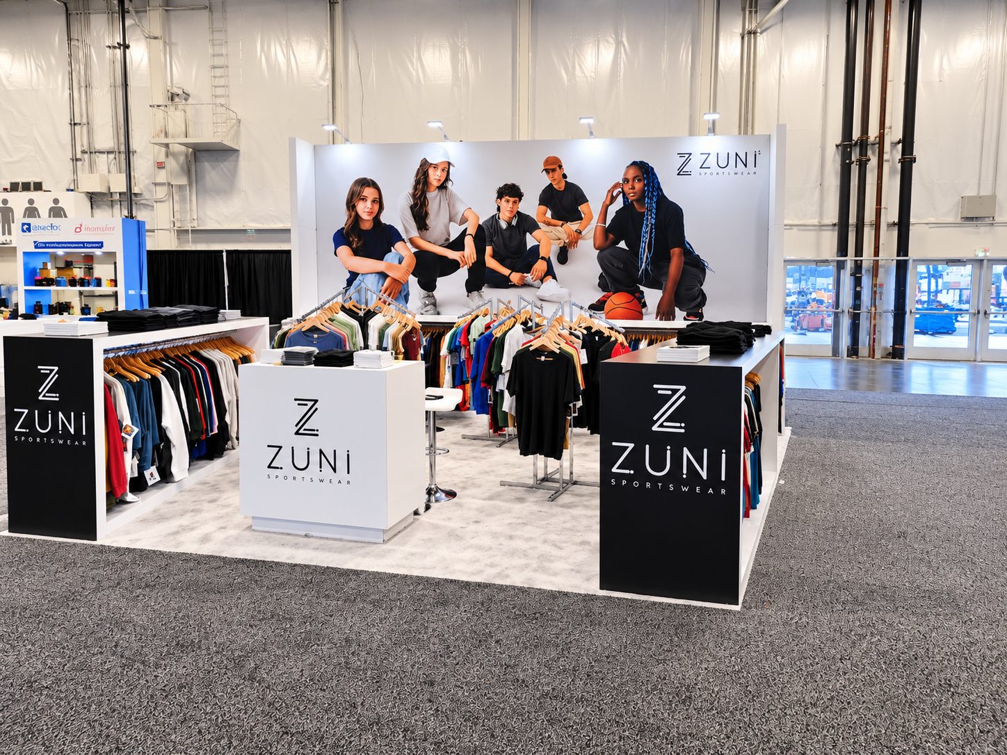 Zuni Sportswear booth with the five-model graphic, black end panels, and garment racks